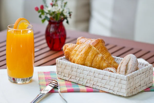 Snídaně s kávou a croissanty v košíku na stole — Stock fotografie