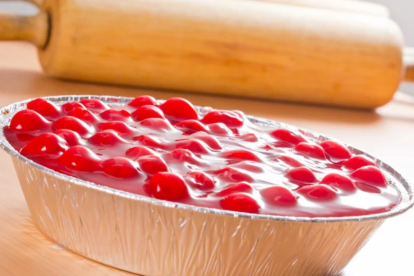 Raspberry cheese cake with kitchen tools on wood table. — Stock Photo, Image