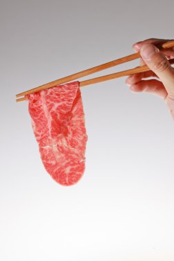 yemek çubukları arasında tutulan çiğ et parçası.