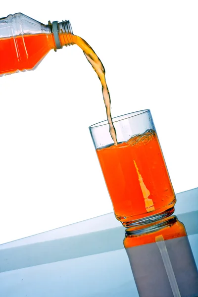 Bevanda arancione versando in vetro da bottiglia di plastica — Foto Stock
