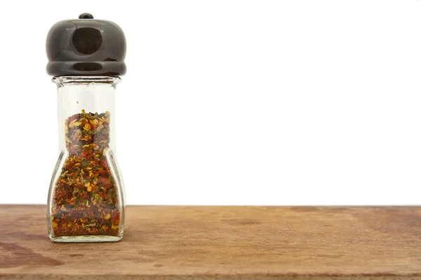 Spices in pepper shaker on wooden board — Stock Photo, Image