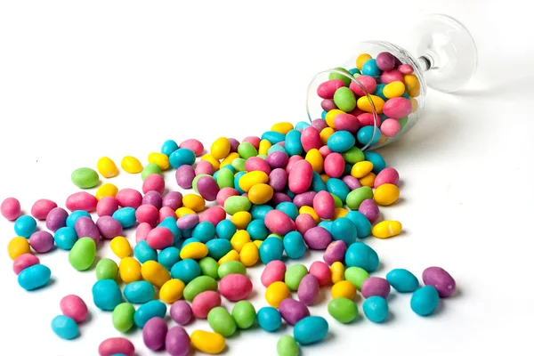 Color candie beans spilt from glass on white background — Stock Photo, Image