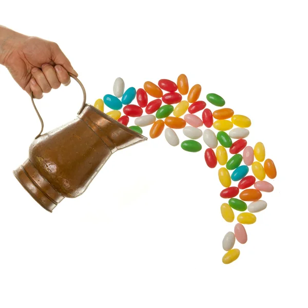 Mano vertiendo caramelos de color de jarra de estaño —  Fotos de Stock