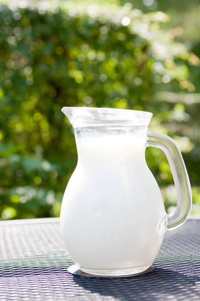 La leche fresca en la jarra de cristal sobre la mesa — Foto de Stock