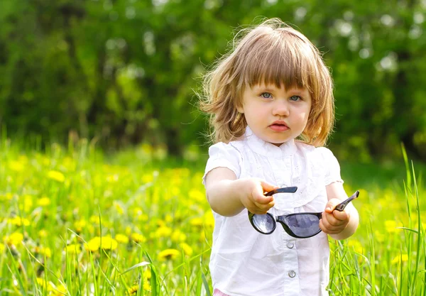 Petite fille dans une prairie avec des lunettes de soleil — Photo