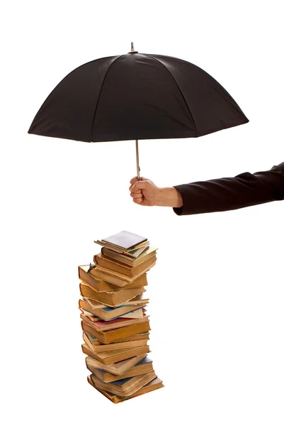 Mano sostiene paraguas negro protegiendo pila de libros antiguos — Foto de Stock