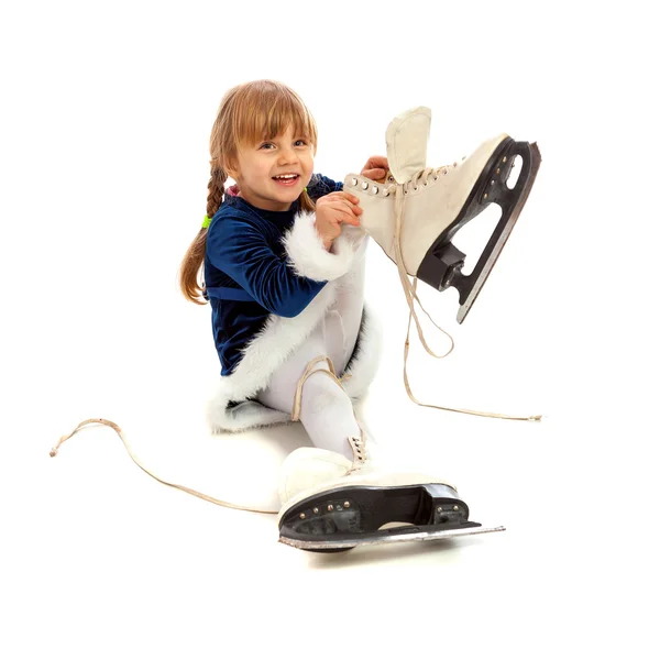 Little girl in blue dress putting on big skates — Stock Photo, Image