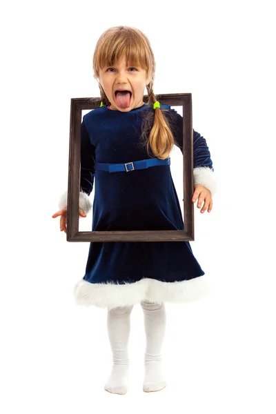 Little girl looking trough wooden frame and showing her tongue — Stock Photo, Image