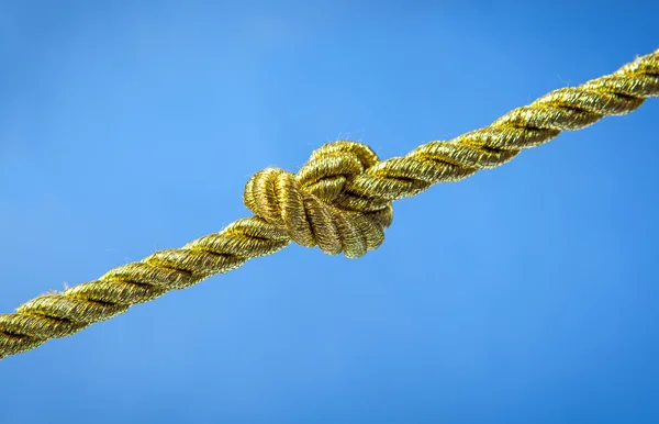 Gouden touw knoop op blauw — Stockfoto