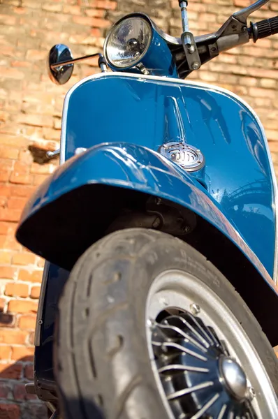 Blauwe scooter voor een rode bakstenen muur — Stockfoto