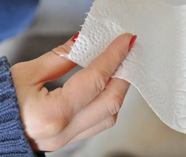 Mulher com unhas vermelhas tomando papel higiênico — Fotografia de Stock