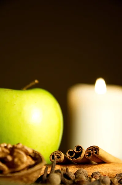 Зеленое яблоко, корица, грецкий орех и свеча — стоковое фото