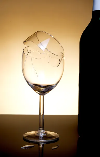 Botella de vid y vidrio roto sobre fondo naranja — Foto de Stock