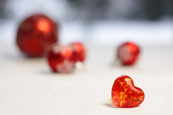 Små röda glas hjärta med röda julgranskulor — Stockfoto