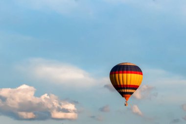 Masmavi gökyüzünde beyaz bulutların arka planına karşı parlak renkli bir balon