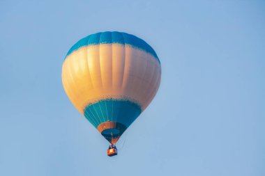 Mavi gökyüzünde şafak vakti mavi bir balon. Güneş ışınları yansıtılır