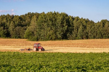 Açık bir günde traktör tarlayı sürüyor.