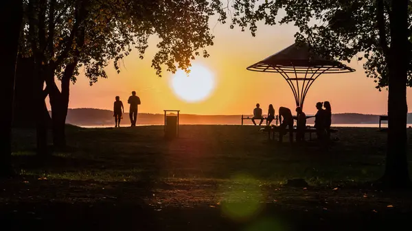 Plajda huzurlu bir yaz günbatımı. Akşamları yürüyen insanların siluetleri.