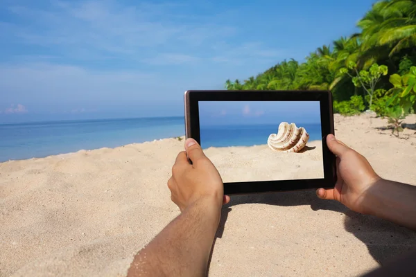 Manos sosteniendo la tableta PC en la playa — Foto de Stock