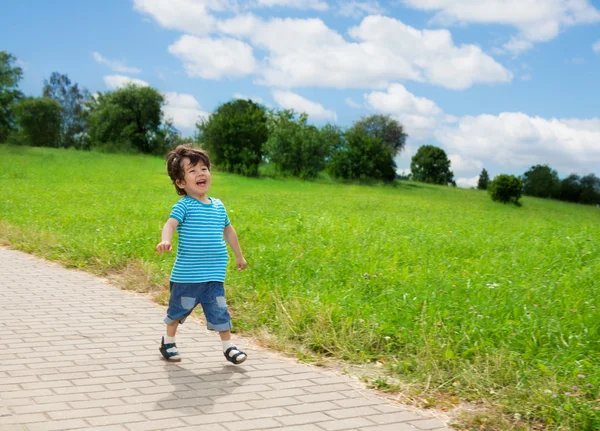 En liten gutt løper i parken – stockfoto