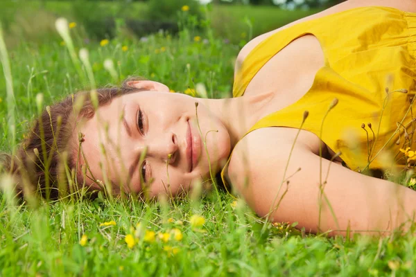 Menina que estabelece na grama verde — Fotografia de Stock