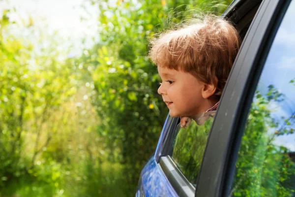 Niño curioso mirando fuera de la ventana del coche — Foto de Stock