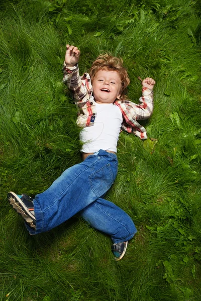 Хлопчик сміється котиться на траві — стокове фото