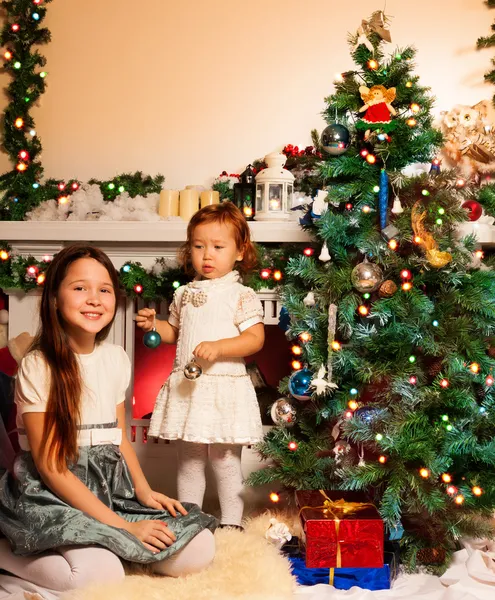 Menina com sua irmãzinha decorando árvore de Natal — Fotografia de Stock