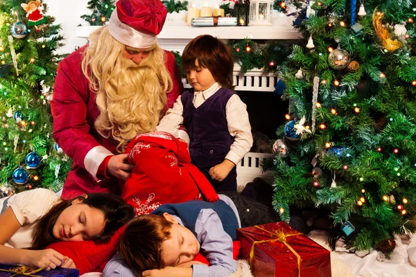 Criança procurando presentes na bolsa do Papai Noel com presentes — Fotografia de Stock