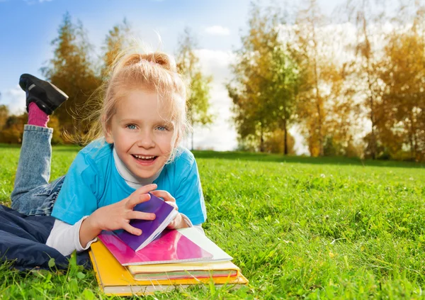 Roztomilá holčička s knihami v parku — Stock fotografie