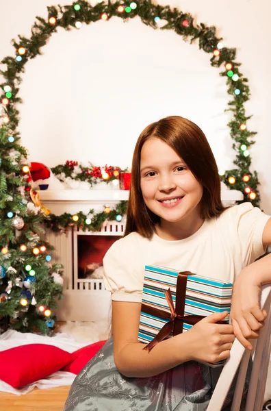 Petite fille assise près de la cheminée avec cadeau — Photo