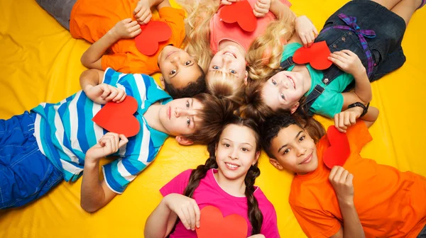 Группа детей лежит с красными сердцами — стоковое фото