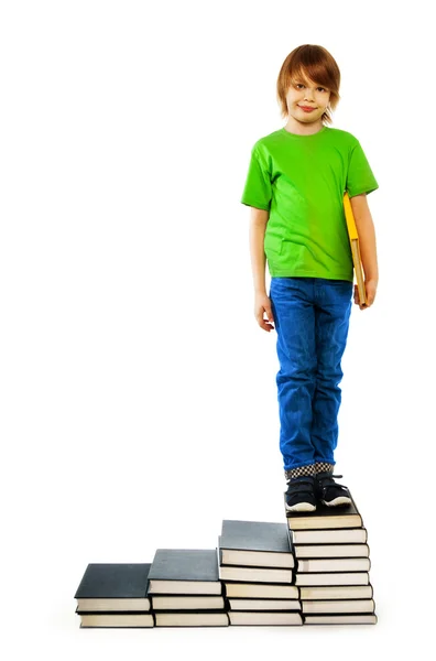 Boy standing on stairs of books — Stock Photo, Image