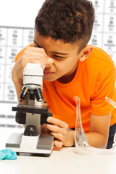 Menino preto olhando no microscópio — Fotografia de Stock