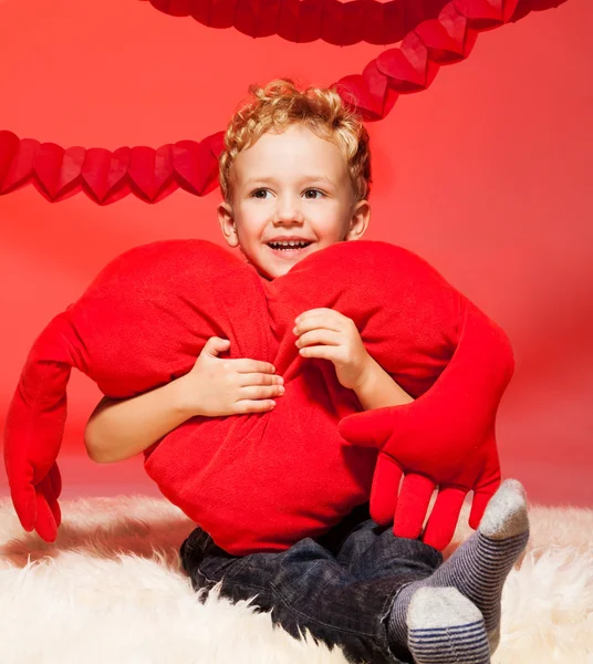 Pequeño chico rubio con almohada de corazón — Foto de Stock