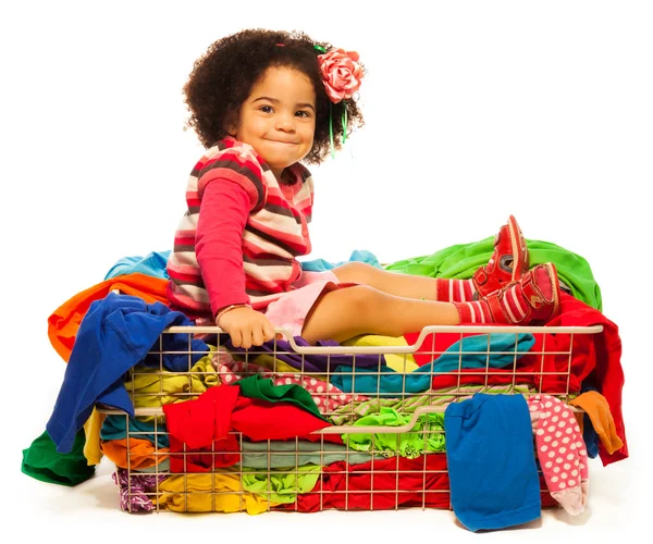 Black girl sitting in the basket with clothes — Stock Photo, Image