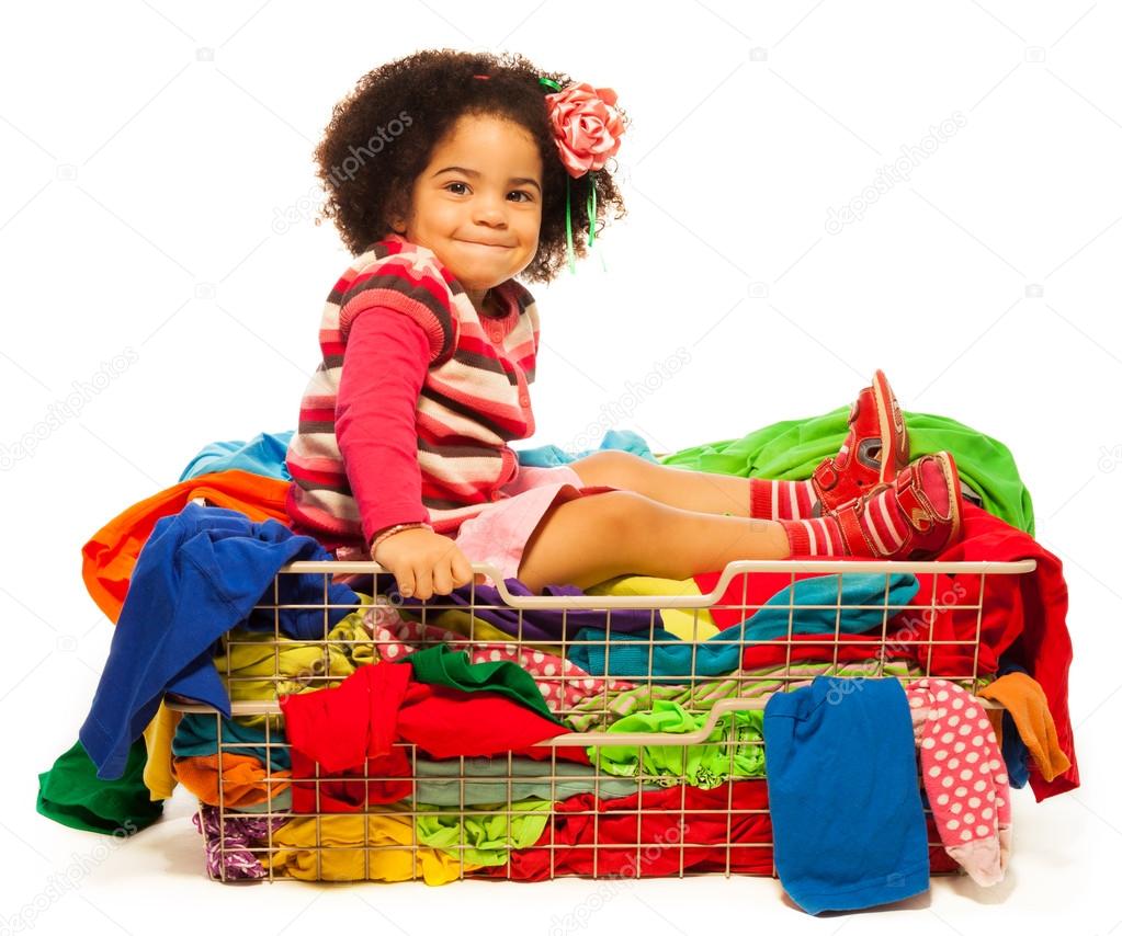 Black girl sitting in the basket with clothes