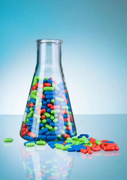Vidro cheio de comprimidos coloridos e comprimidos no chão — Fotografia de Stock