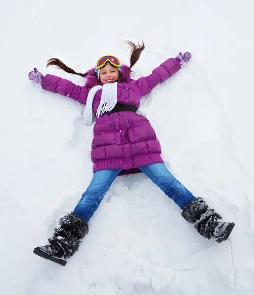 Chica tendida en forma de estrella en la nieve — Foto de Stock