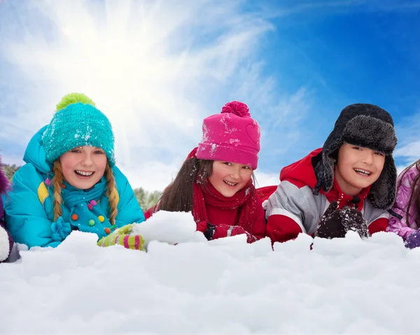 Tre bambini sdraiati sulla neve — Foto Stock