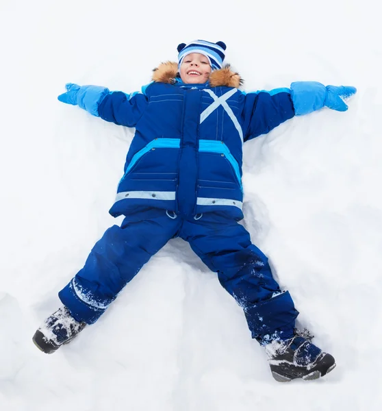 Kleine jongen leggen in stervorm in sneeuw — Stockfoto