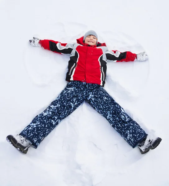 Niño tendido en forma de estrella en la nieve —  Fotos de Stock