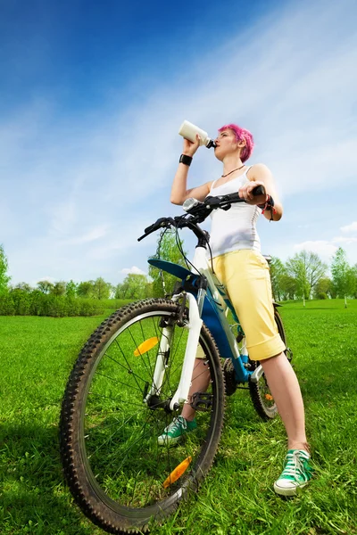 Jonge vrouw op een fiets drinkwater — Stockfoto