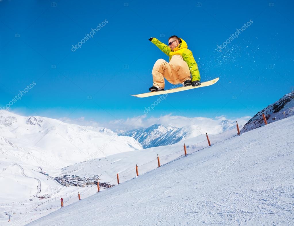 Cute snowboarder man jumping on ski resort