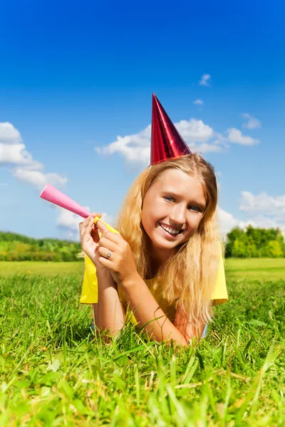 Blond girl lay with noisemaker — Stock Photo, Image