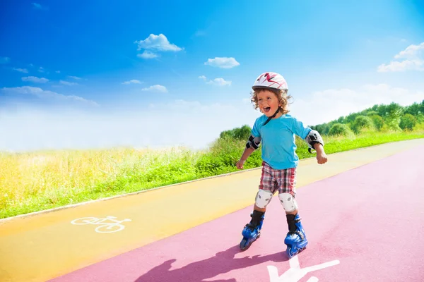 Šťastný chlapec řítí z kopce na kolečkových bruslích — Stock fotografie