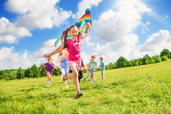 Beautiful girl run with kite together with friends