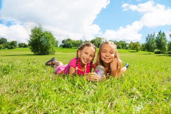 Две девушки в траве с бабочкой — стоковое фото