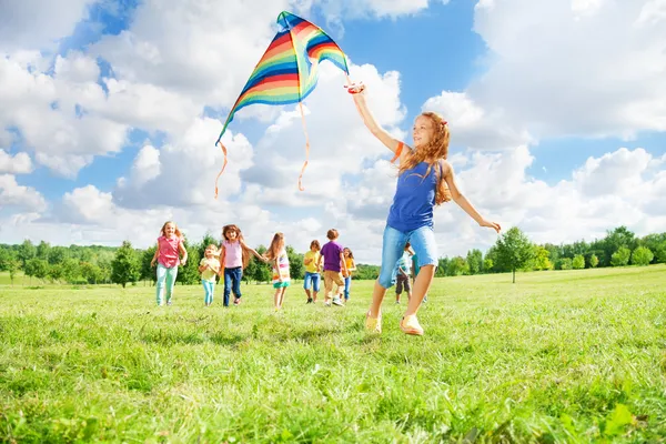 Chica corriendo con cometa con amigos — Foto de Stock