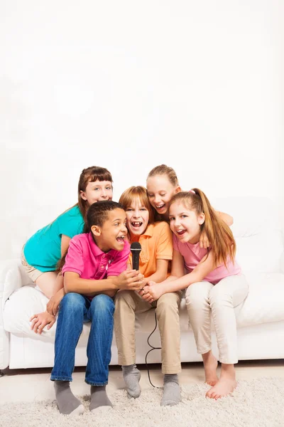 Группа детей поет на диване — стоковое фото